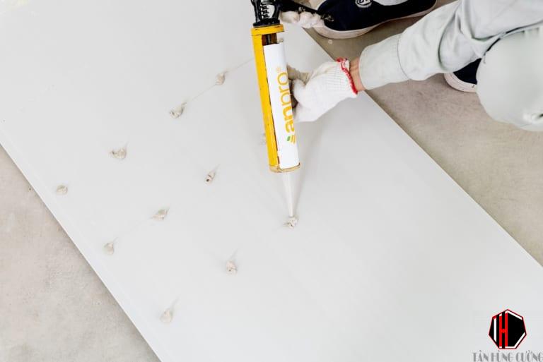 Báo Giá Thi Công Tấm Nhựa Giả Đá | Tấm pvc vân đá Ốp Tường Bao Nhiêu Tiền 1M2 14 Bôi keo lên bề mặt sau của tấm, có thể điểm thêm băng dính 2 mặt để có sự kêt dính chặt hơn